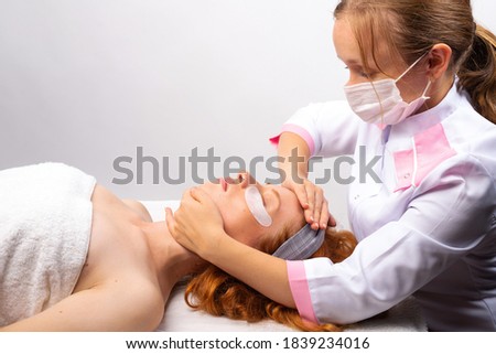 Beautician makes a professional facial massage to a young girl. Healthy skin concept. Photo on white background