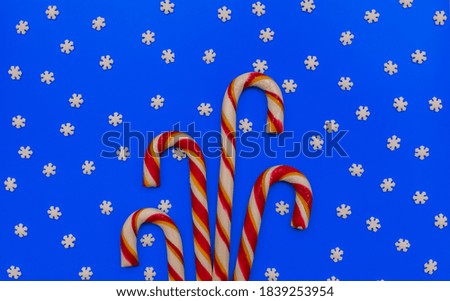 Christmas concept. Striped caramels and snowflakes on a blue background. Red and white candy. Flat lay, copy space, top view. New Year.