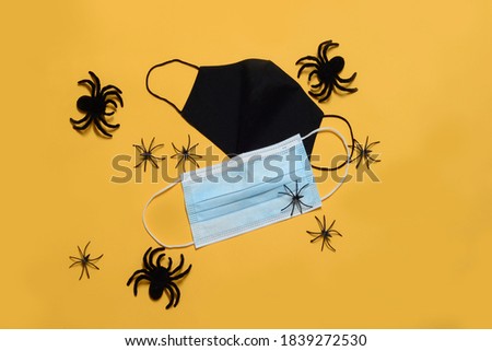 Anti-virus protective face masks next to spiders on yellow background, close up