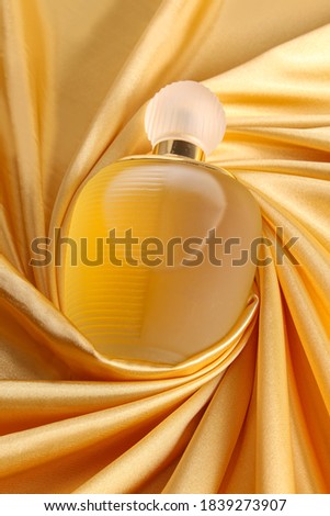 Perfume bottle on Gold silk folded fabric background fragrance perfume bottle on dark empty background. Top view. 