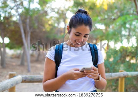 Young beautiful woman standing at the forest on a sunny day, smiling happy and cheerful chatting on the phone