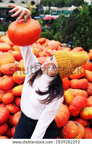 
Teenager girl in woolen yellow hat and scarf posing at harvest farm and pumpkin patch