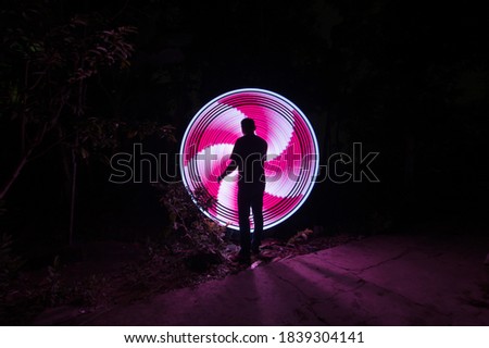 One people standing alone against a red and white circle light painting as the backdrop