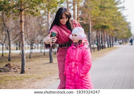 Mom and daughter take a selfie in the park. The child walks with his mother in winter.