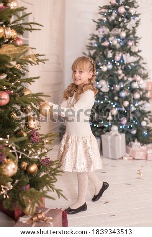 Little girl spends time decorating the Christmas tree. Preparing for the holidays. Santa will be glad.
