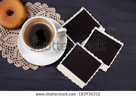 Coffee cup, donut and old blank photos, on wooden background