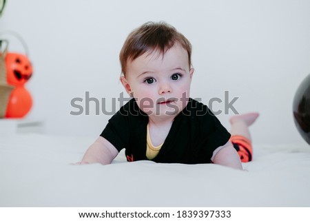 cute baby girl in halloween costume at home, sitting on bed with Halloween decoration, Lifestyle indoors