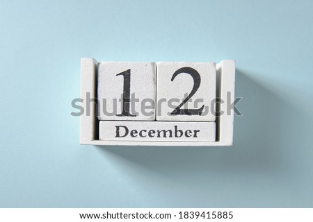 Wooden white calendar on blue background, date 12 December
