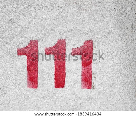 RED Number 111 on the white wall
. Spray paint.