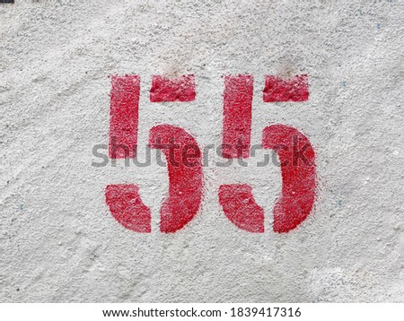 RED Number 55 on the white wall
. Spray paint.