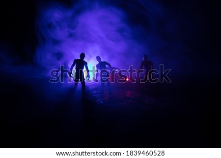 photo of a car stopped on the road lighting up a zombies. Silhouette terrible zombie night near the car. Miniature decoration. Selective focus