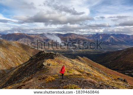 Woman Backpacking along Scenic Hiking Trail surrounded by Mountains in Canadian Nature. Taken in Tombstone Territorial Park, Yukon, Canada.