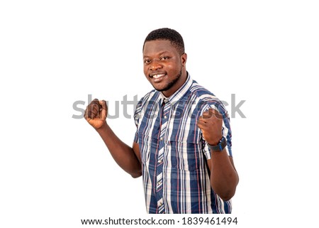 portrait of a handsome happy young man making a winning gesture with raised arms while smiling at the camera.