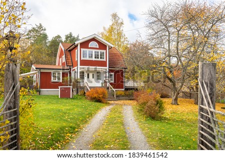 Old traditional red wooden house in Sweden. Countryside in autumn day. View of beautiful European garden design. Golden, yellow, brown, red colors of leaves. Royalty-Free Stock Photo #1839461542