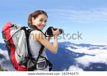 Young woman with backpack taking a photo on the top of mountains, asian