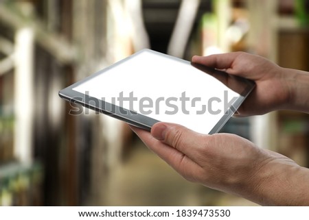 Wholesale trading. Man using WMS app on tablet at warehouse, closeup  Royalty-Free Stock Photo #1839473530