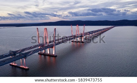 A low angle shot of the Governor Mario M. Cuomo Bridge, also known as the Tappan Zee Bridge. The artfully designed bridge over the Hudson River was illuminated in pink during a cloudy sunset.