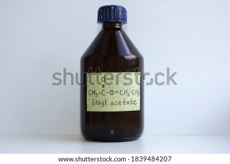 Ethyl acetate in a dark glass jar with a sticker and a chemical formula, the substance is used as a low-toxic solvent, in perfumery, and in the food industry.