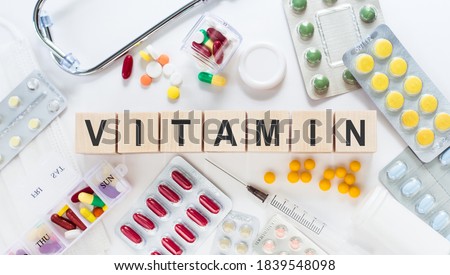 VITAMIN medicine word on wooden blocks on a desk. Medical concept with pills, vitamins, stethoscope and syringe on the background