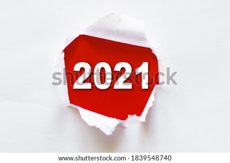 Vision 2021 goal written behind a torn paper. Top view of white torn paper and the text "2021" on a red background .