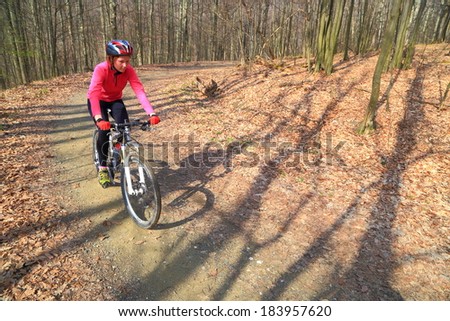 Woman rides a bike on forest road in sunny spring day