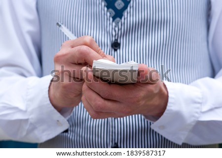 Close-up of mid section of a waiter taking order in a small notepad. Royalty-Free Stock Photo #1839587317
