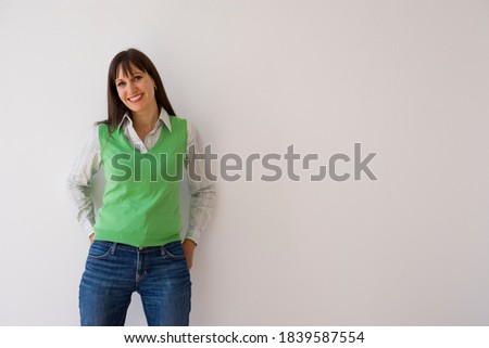 Horizontal three quarter front view of a young woman wearing a green sweater vest smiling at the camera with copy space.