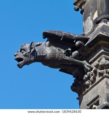 Black gargoyle in the town hall of Leipzig with a blue sky background.