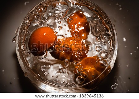 Orange kumquat fruit falls at high speed into a glass container to make sweet or jam Cordoba Argentina