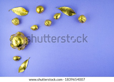 Pumpkins, nuts and leaves painted in gold on a purple background. Flat layout with space for text. High quality photo