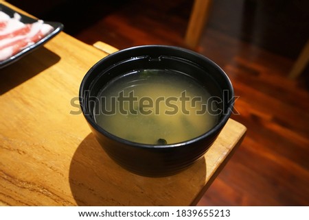 Close up bowl of Miso soup on wooden table, traditional Japanese soup consisting of a stock called "Dashi" into which softened tofu soy paste