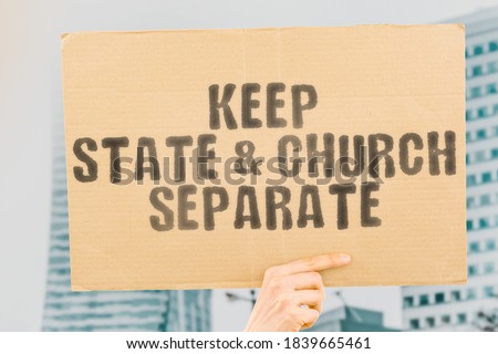 The phrase " Keep state & church separate " on a banner in hand. Human holds a cardboard with an inscription. Religion. Belief. Faith. Government. Sponsoring. Fund. Atheism