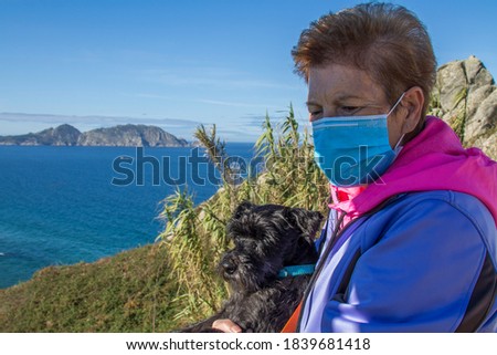 Portrait of senior woman with disposable medical mask and her dog. Safety in public places during the coronavirus outbreak.