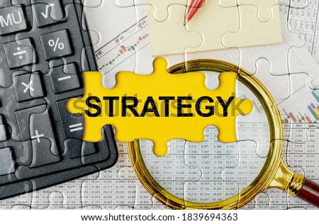 Business concept. Puzzle with a calculator, magnifying glasses and financial documents in the center inscription -STRATEGY
