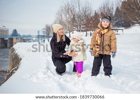 Happy family, mom with son and daughter in winter clothing, winter time, outdoor activity