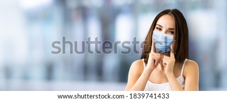 Coronavirus, covid-19, pandemic, protective concept - brunette happy smiling woman wearing showing face protection medical mask, indoors. Copy space blank area for some sign or advertisement ad text.