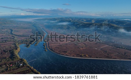 Aerial landscape above lake and hills in a misty day in autumn season