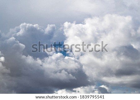 A small piece of blue sky shines through the clouds. Gray white clouds