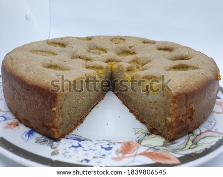 A banana cake on a flower-patterned plate, it tastes crispy on the outside of the crust, sweet, soft, moist and fluffy inside with a banana slice on it isolated on white background. 