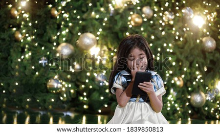 happy asian girl in princess dress chating on Christmas tree in background in merry Christmas and happy new year festival