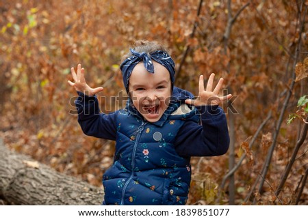 Little girl grimaces at the camera. The girl is alone in the forest.