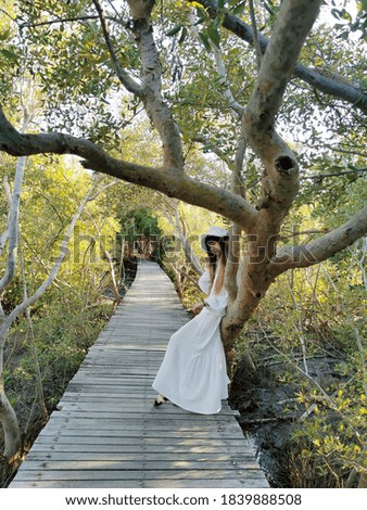 Asian girl in white dresses and white hat sit on twigs