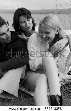 Young beautiful people spending time on the beach. Sea background. Classic clothes. Positive emotions, summer vibes. Black and white classic photo. Fashionable. For print and advertisement
