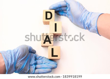 Word DIAL on wooden cubes held by hands in protective gloves on a white background with available space for copying. the medicine