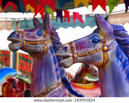 old aged colorful riding horses toys in a playground as circus carousel in a country fair in Thailand. 