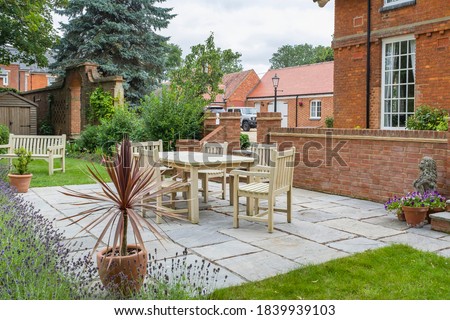 Large UK property, house with back garden, wooden furniture table and chairs on patio terrace