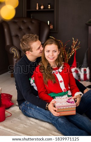 Merry Christmas and Happy New Year!. Young couple celebrating holiday at home. Man and woman unpack gifts