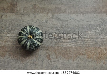 Minimal Autumn concept: a green pumpkin on a wooden rustic background