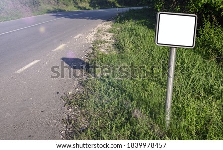 A blank small road sign next to the highway. White square sign on post pole, mock up image.
