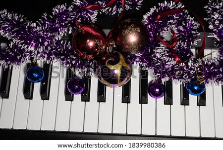 New Year's composition. Lilac tinsel and Christmas balls are on the piano keys.
